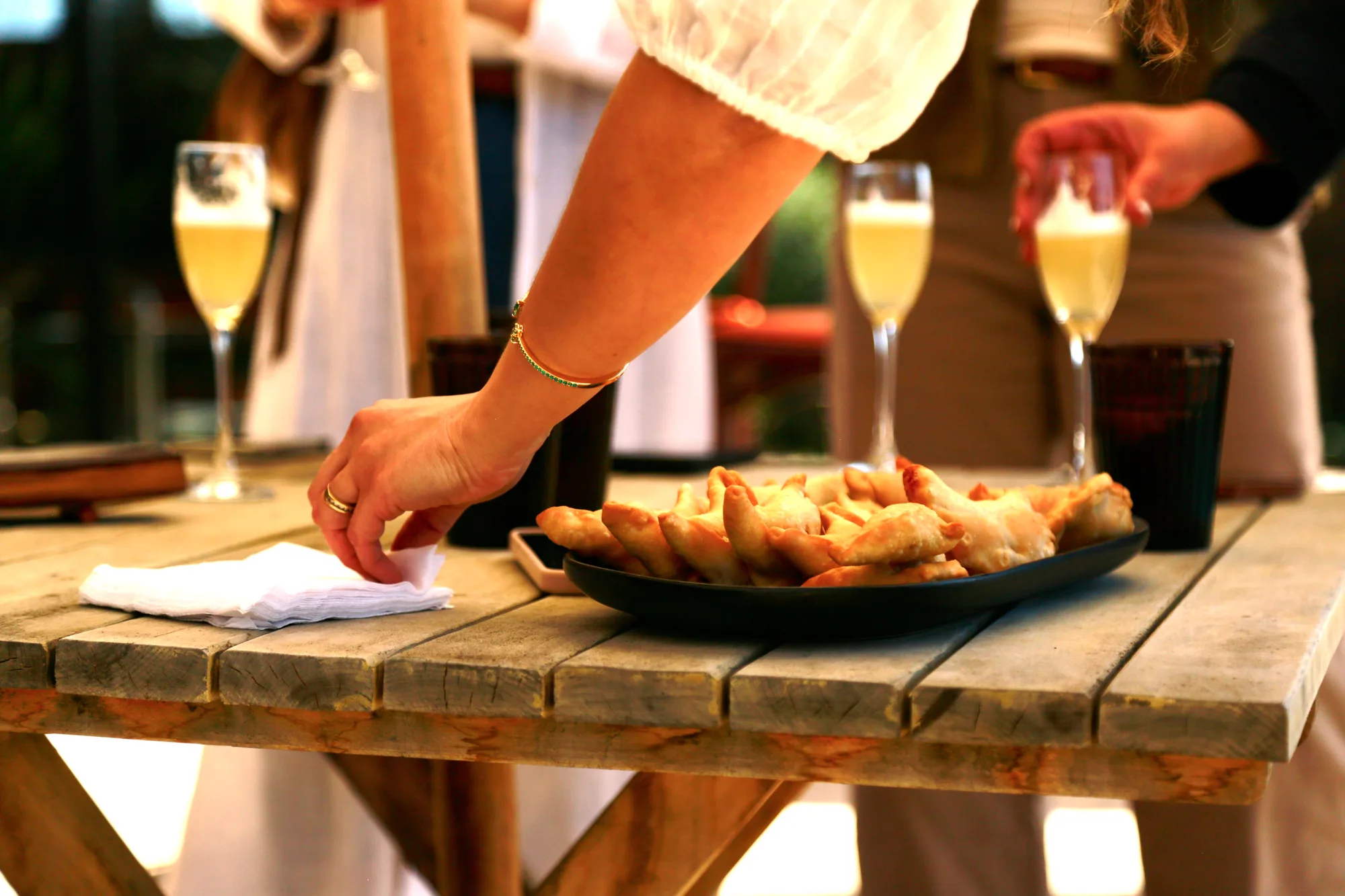 A plate of empanadas, with glasses of sparkling wine alongside