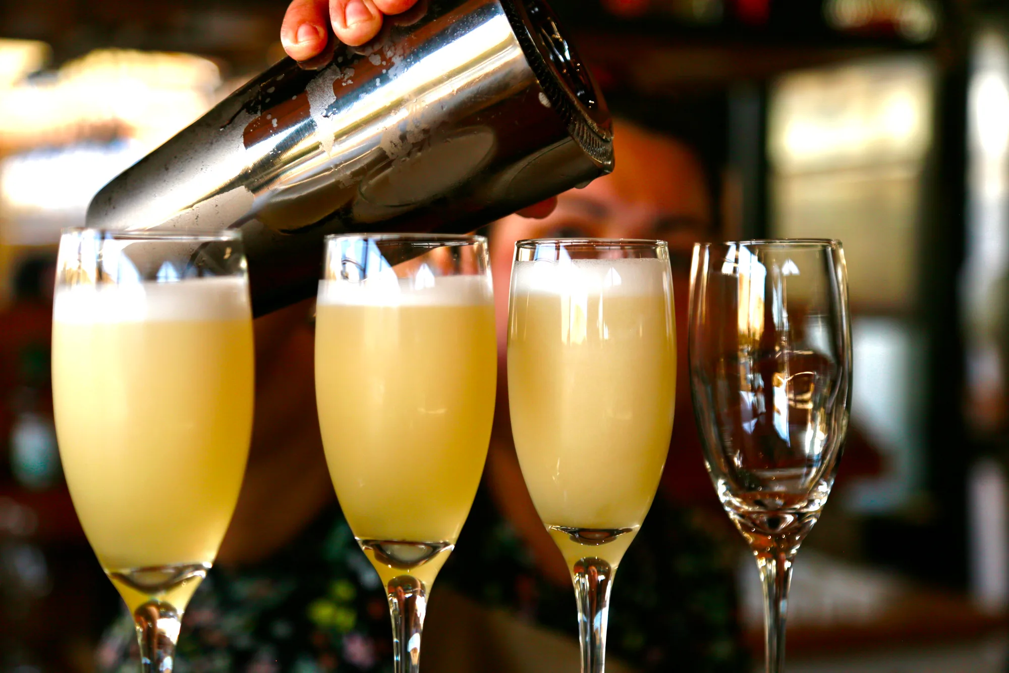 A round of pisco sours being shaken and poured into glasses