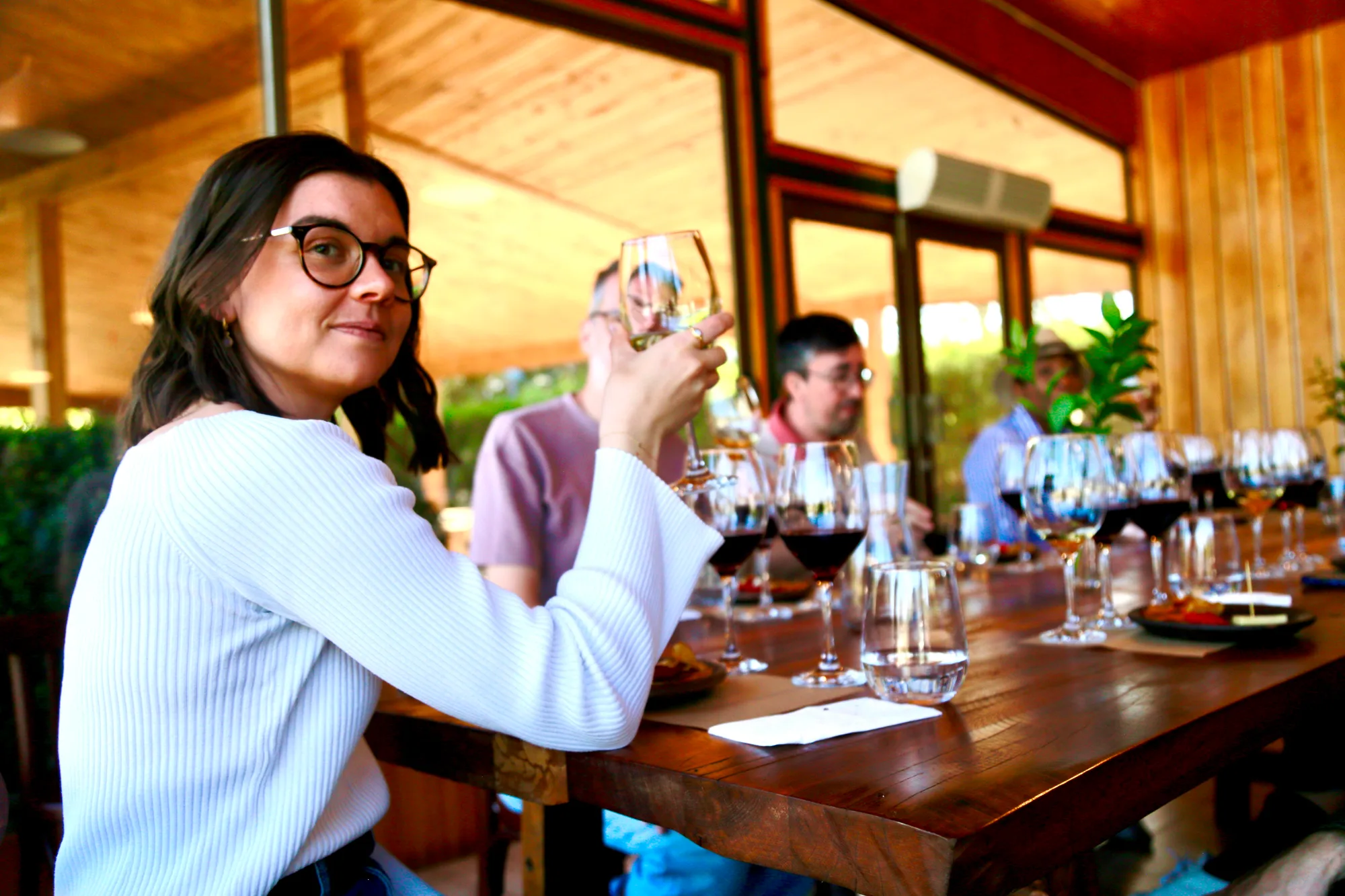 A guest examining a glass of red wine at the long table